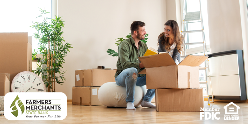 Couple smiling at each other in front of a stack of boxes as they are packing up their house