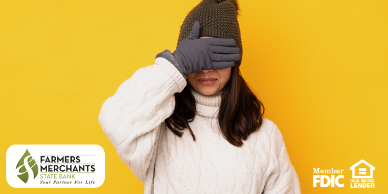 Woman in sweater and winter hat with gloves on and her hand over her eyes