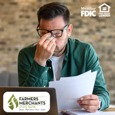 Man wearing glasses with a pen in his hand and his hand pinching the bridge of his nose in stress