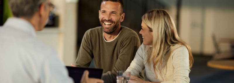 Couple sitting and smiling with financial advisor