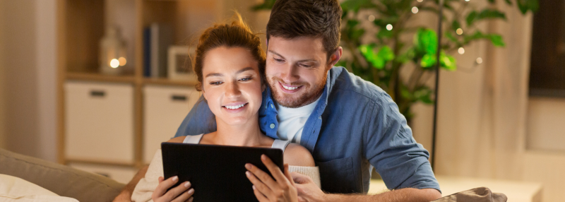 Man and woman looking at homes together on a tablet in their living room