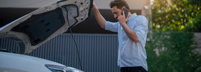Man on the phone with the hood of his car open