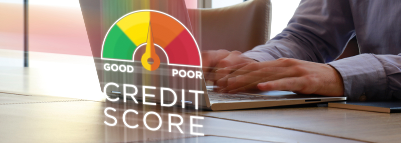 Man sitting at table with hands on laptop keyboard and illustration of good to poor credit score meter with arrow in the middle