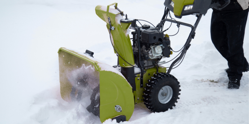 Man pushing snowblower outside in the snowy environment