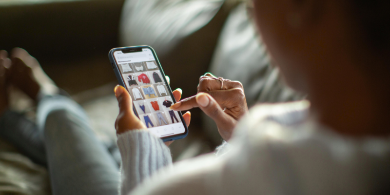 Woman lying on the couch shopping for clothing on her smartphone