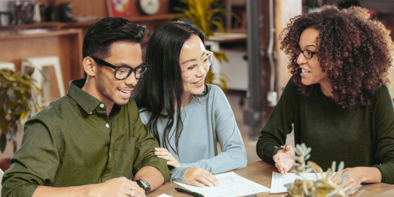 Male and female couple speaking with female mortgage lender in an office