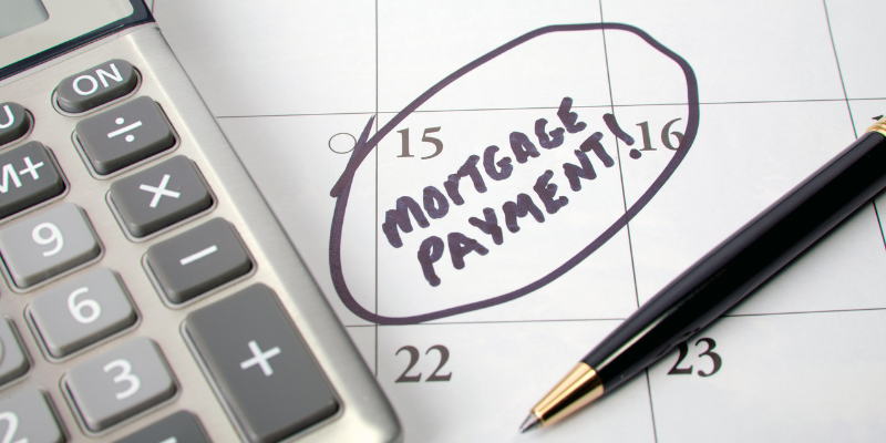 Calendar with writing 'Mortgage Payment' on it circled in black pen with pen and calculator next to it
