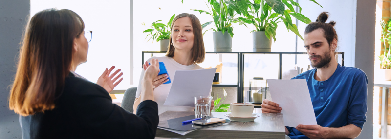 Man and woman meeting with mortgage lender and looking at paperwork together