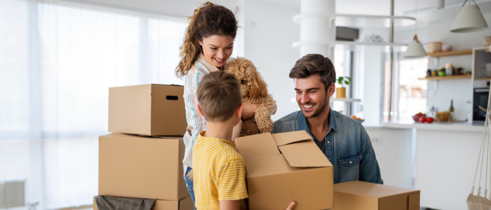 Happy family with son and dog moving boxes into their new home
